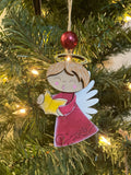 Decorative angel ornament on a Christmas tree with lights.