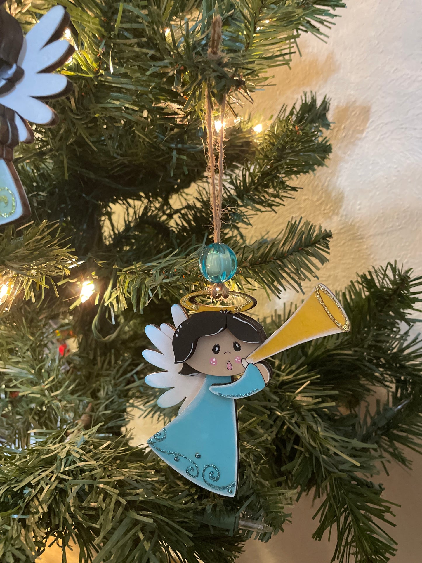 Decorative angel ornament on a Christmas tree with lights in the background