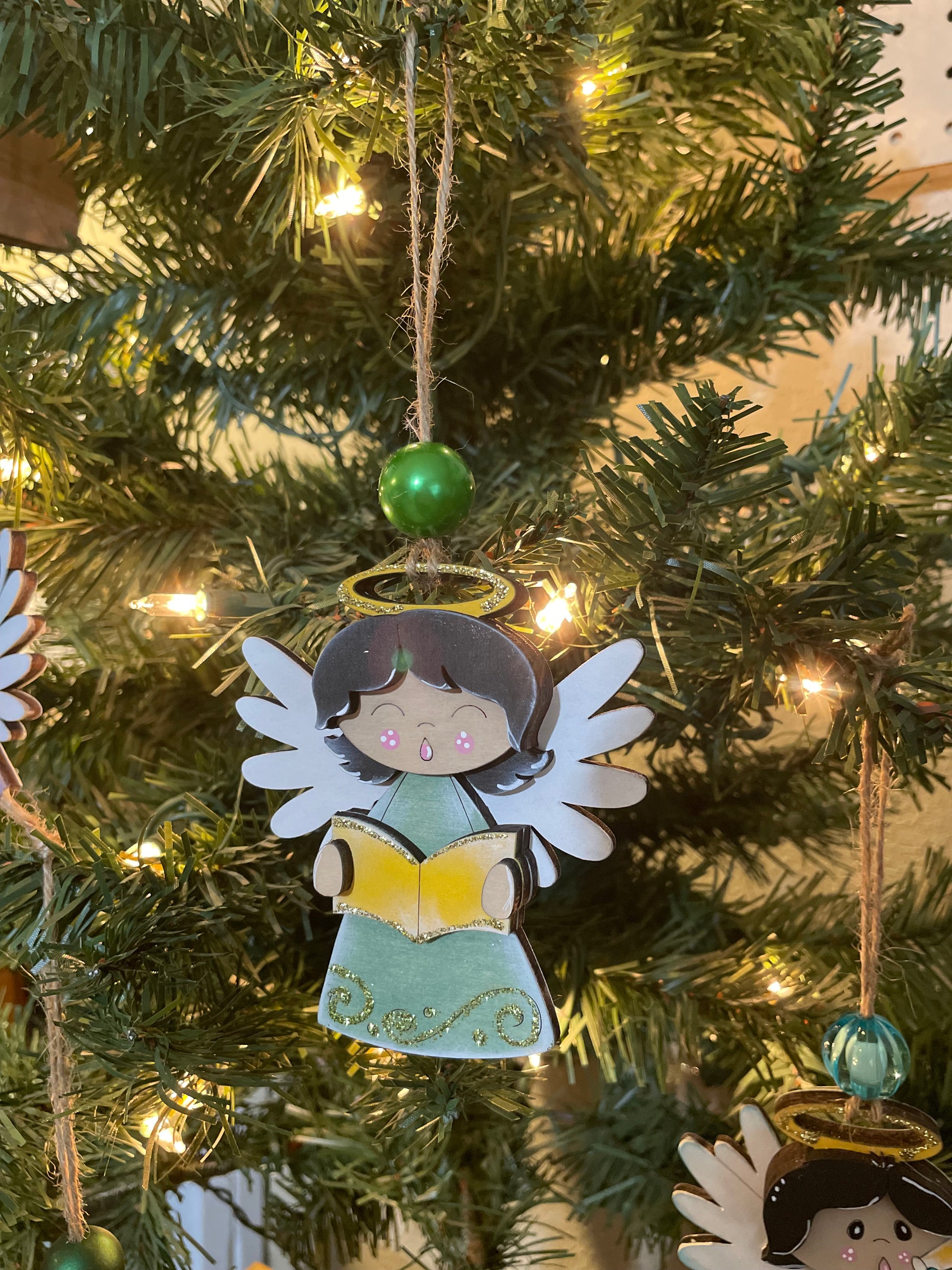 Decorative Angel ornament on a Christmas tree with an open choir book.