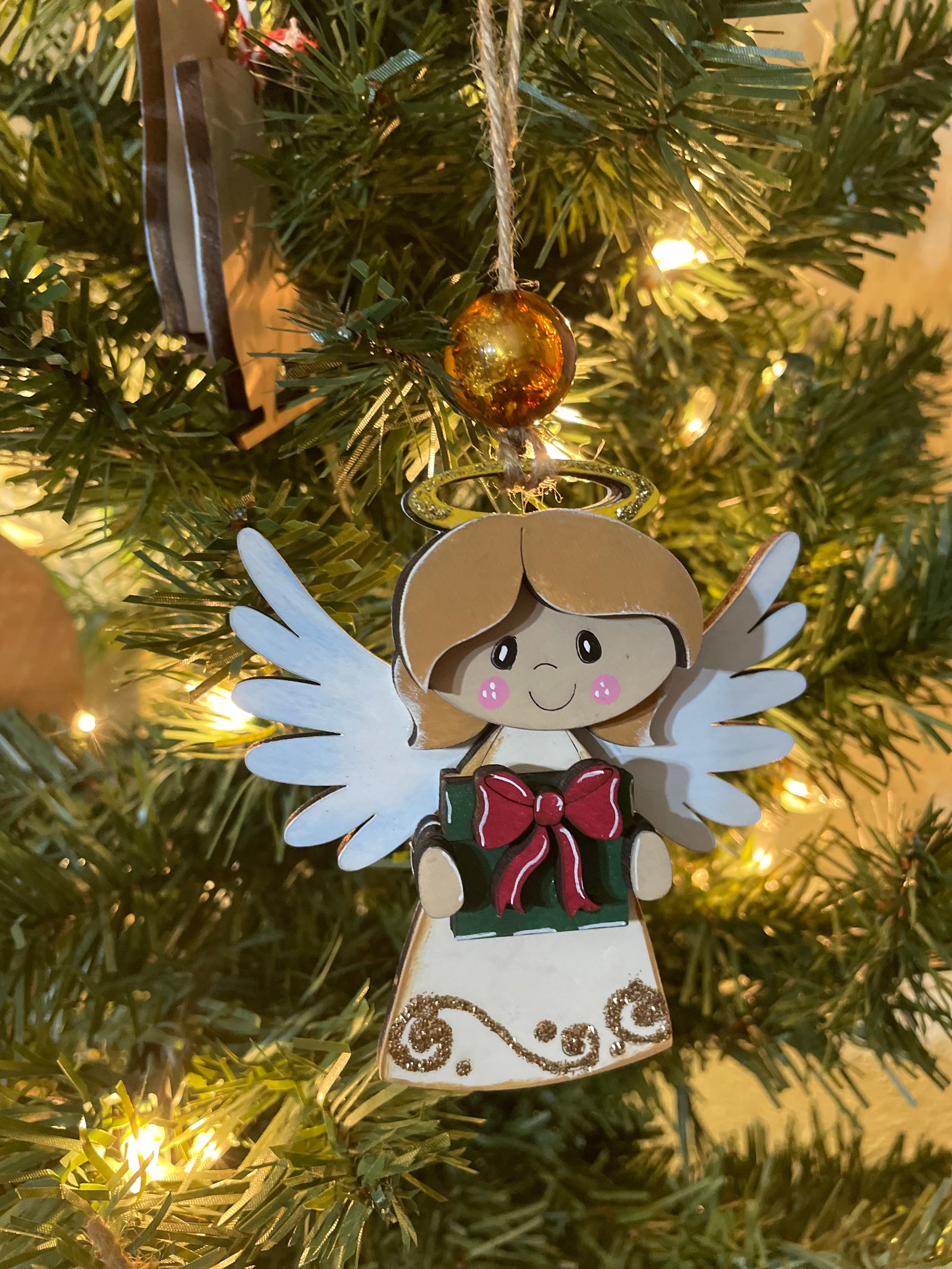 Decorative Angel ornament with a gift on a Christmas tree.