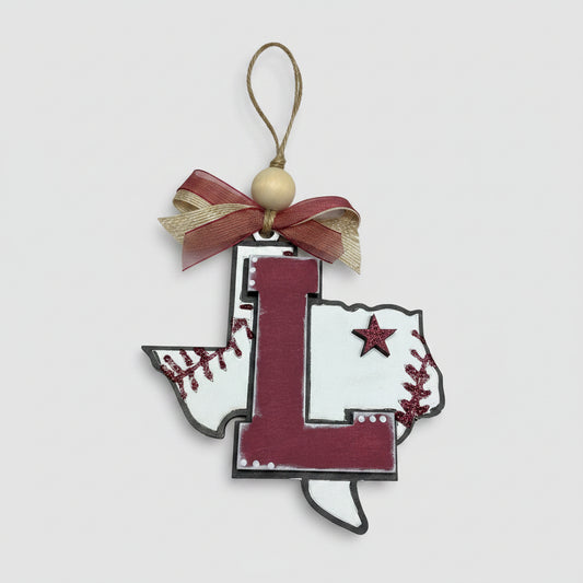 Decorative item with a large letter 'L' and baseball-themed design on a wooden background in the shape of Texas. 